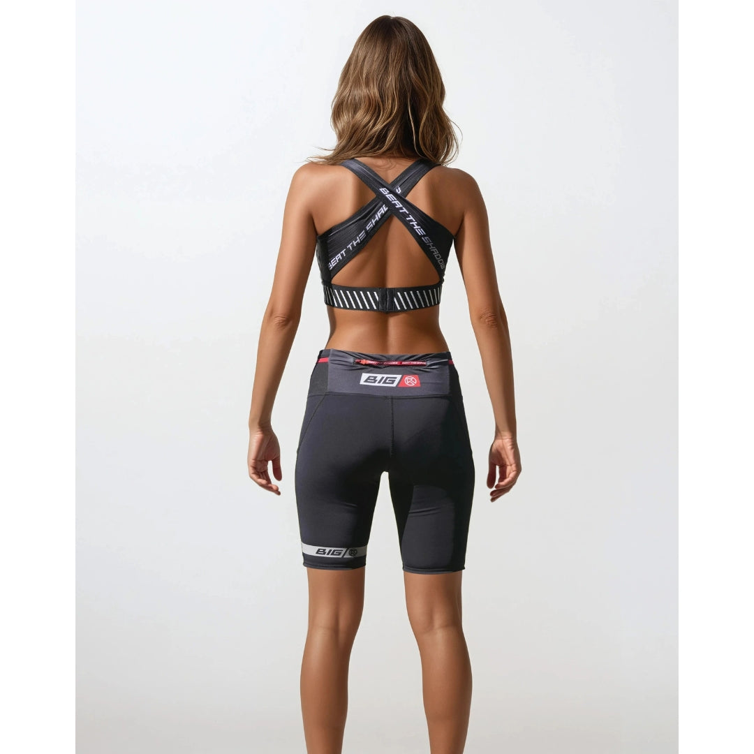 Woman wearing a black athletic outfit with visible branding on a white background