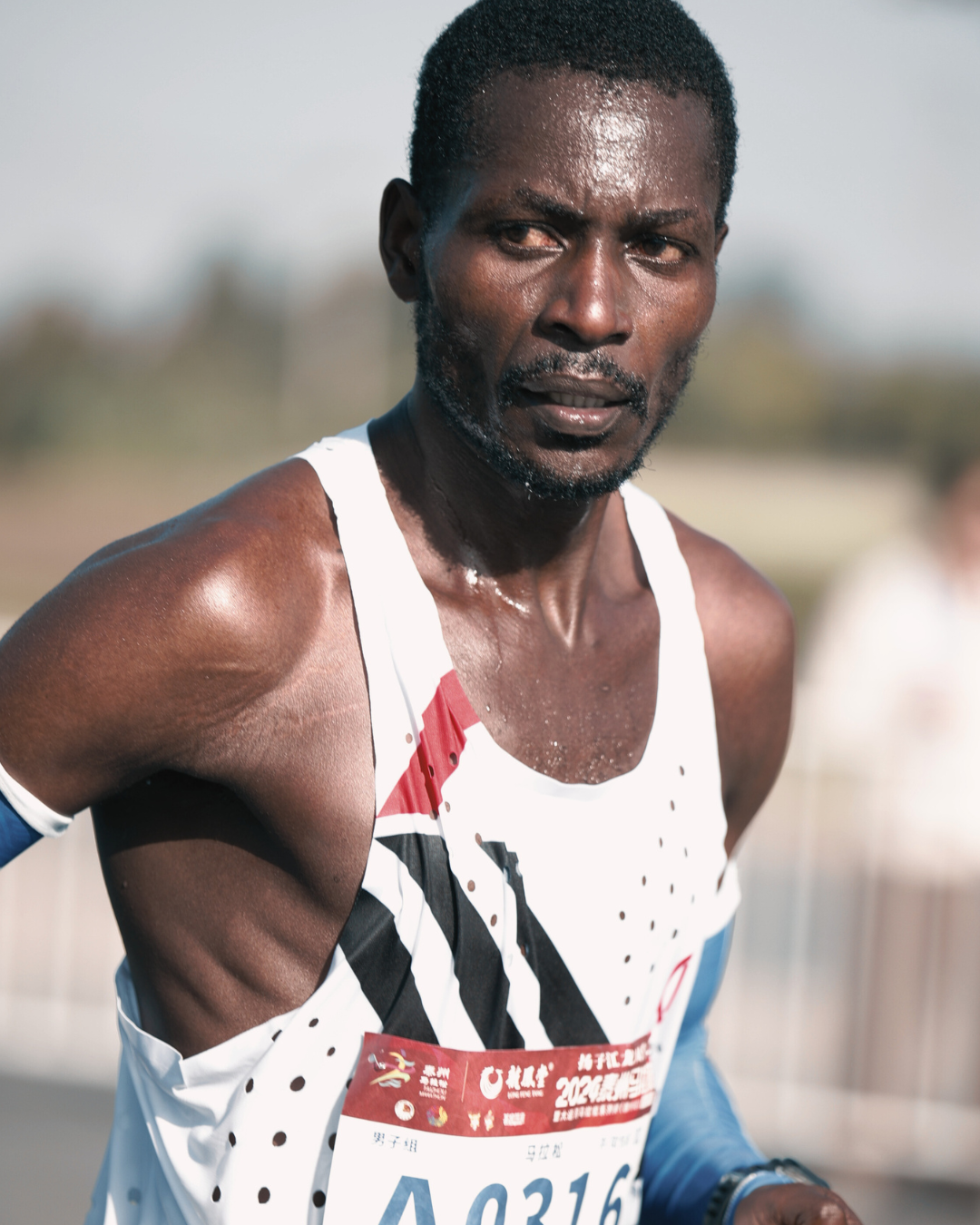 Athlete in a white tank top with a race bib during a race